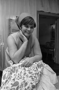Fashion designer Lily Pulitzer, wearing a headscarf and sleevless top, being interviewed with her printed fabrics in her studio