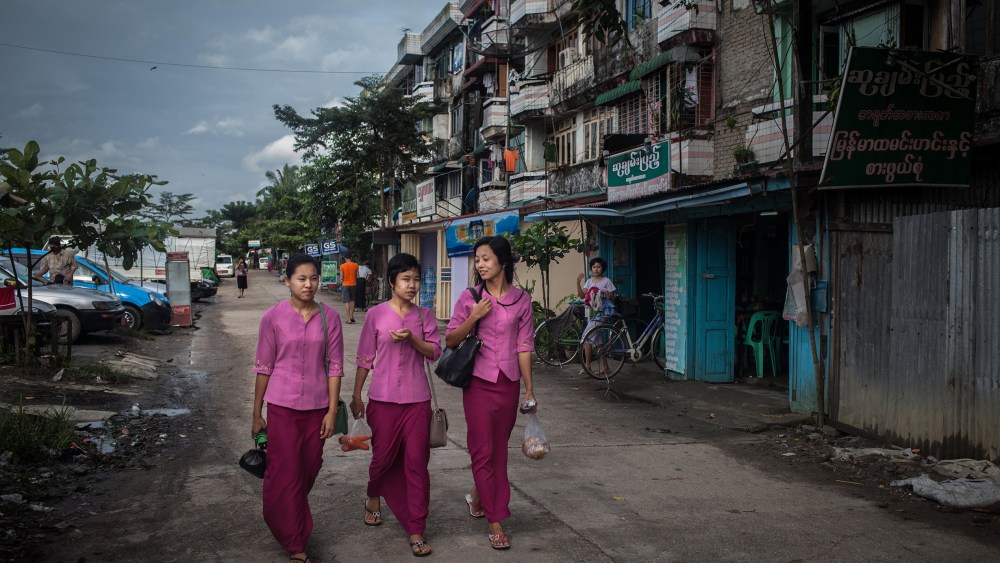 Garment factory workers walk to work from their dormitories on October 13, 2015. On August 29 2015, the government of Myanmar announced a minimum wage of 3,600 kyats (about 3 US$). This slight pay raise was met with hostilities by factory owners in the Garment Industries who either refused to increase pay at all, made layoffs to keep expenses the same or cut overtime pay and benefits. Even those garment factory workers who have seen a increase in their daily wages have seen very little change in their salaries overall.