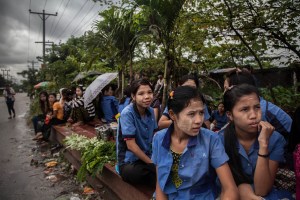 Factory workers listen to their Union Leader speak on October 13, 2015. On August 29 2015, the government of Myanmar announced a minimum wage of 3,600 kyats (about 3 US$). This slight pay raise was met with hostilities by factory owners in the Garment Industries who either refused to increase pay at all, made layoffs to keep expenses the same or cut overtime pay and benefits. Even those garment factory workers who have seen a increase in their daily wages have seen very little change in their salaries overall.