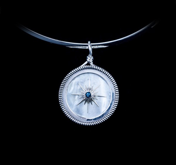 Vela's North Star necklace has a mother of pearl backdrop.