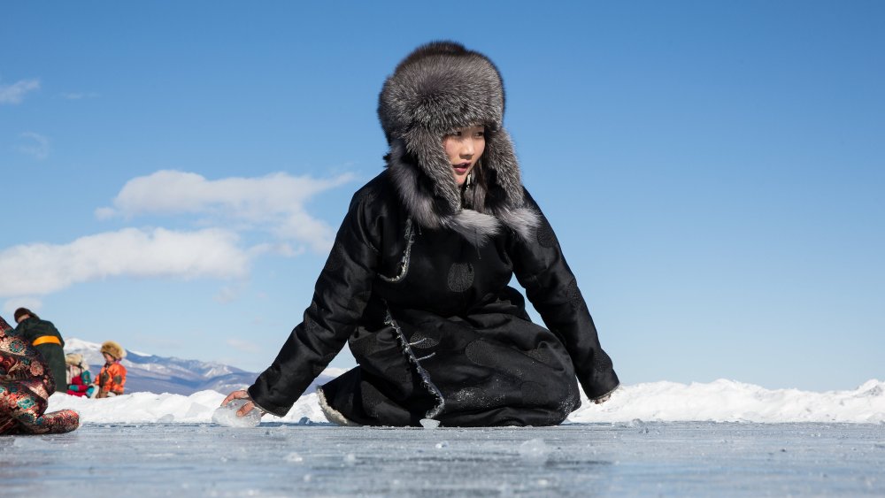 A young Mongolian woman plays a game sliding pieces of ice at the Lake Khovsgol Ice Festival in Khatgal, Mongolia, on March 4, 2017.
