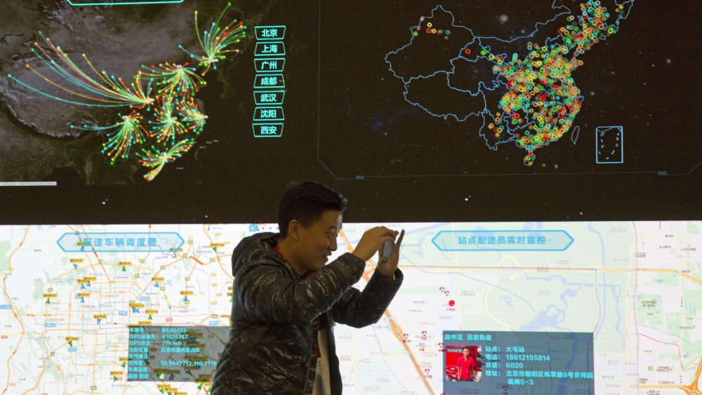 A man takes a photo in front of a display tracking packages across China at JD.com's Beijing command center.