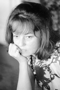 Outtake; Portrait of French actress Jeanne Moreau wearing a loose chemisey dress of orange silk with black scroll print and no make-up during an interview with Women's Wear Daily in Paris, France, circa August 1964.Article title: "La Moreau"