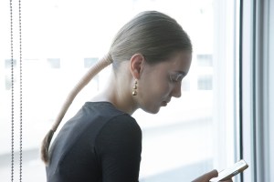 To counterbalance the feminine clothing, Holli Smith for Oribe gave models a tight ponytail wrapped in two yards of natural toned leather. “I love this Alexander McQueen and Steven Klein shot in the Nineties of these loops of gauzy cloth [in the hair],” she said on the inspiration. Smith prepped the hair with Oribe Volumista Mist to accentuate the natural texture and secured the leather strap by sewing the material at the top and bottom.