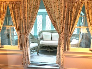 A sunroom balcony off of a guest bedroom with original wicker settee & 2 chairs