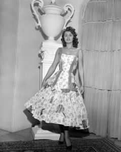 Loren Scicolone Italian actress Sophia Loren wears a cocktail dress of cyclamen printed taffetta with an H-line treatment of lilac ribbon ending in bows above a deep flounce, designed by Emilio Schuberth of Rome, in RomeFASHION SOPHIA LOREN 1955, ROME, Italy