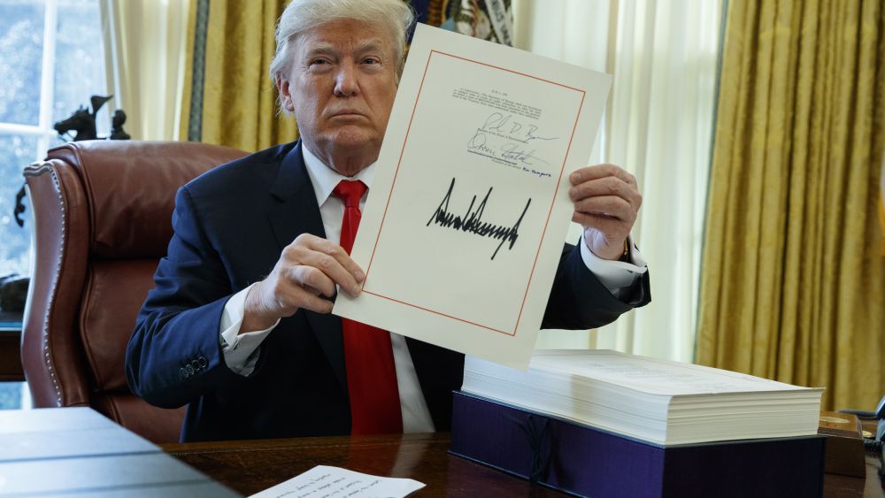 President Donald Trump shows off the tax bill after signing it in the Oval Office of the White House, in WashingtonTrump, Washington, USA - 22 Dec 2017