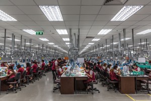 Employees use precision tools to set gemstones into wax “trees” that will hold them in place.