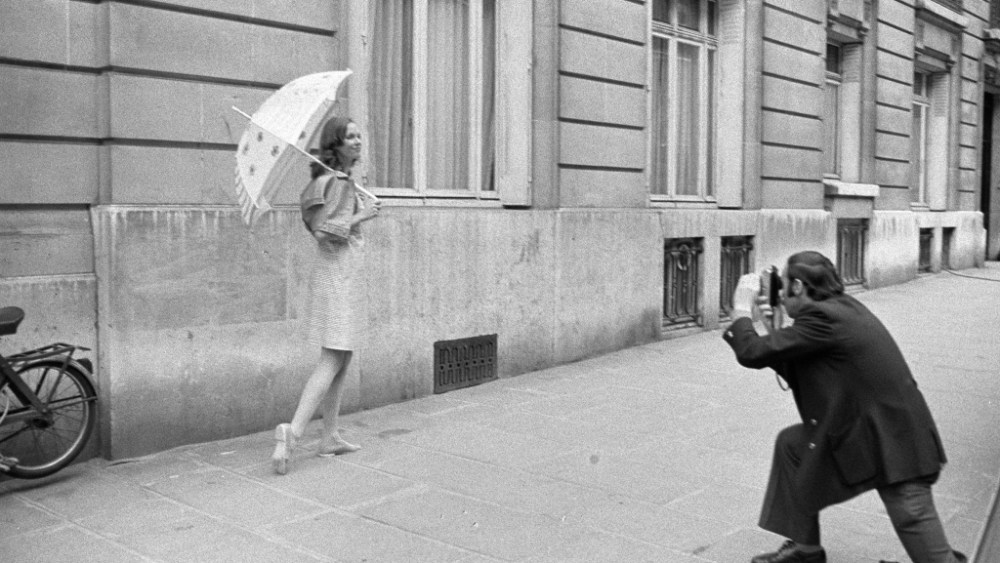 Photographer shooting a model wearing Courreges and holding an umbrella on the streets of Paris *** Local Caption ***
