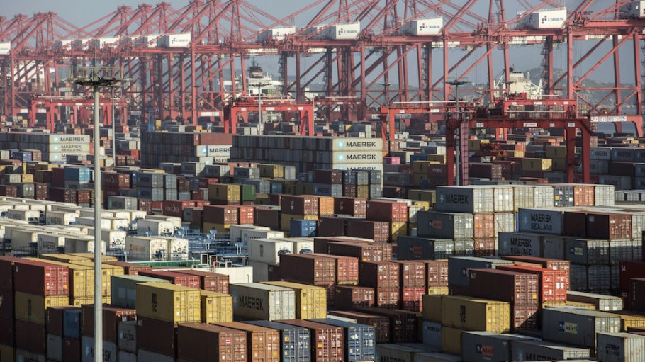 Containers sit stacked next to gantry cranes at the Yangshan Deep Water Port in Shanghai, China