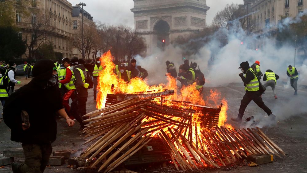 Demonstrators run by a burning fire near the Arc de Triomphe during a demonstration Saturday, Dec.1, 2018 in Paris. Paris police say at least 63 people have been arrested in violent clashes between protesters and police amid nationwide demonstrations against rising taxes and President Emmanuel Macron's policiesGas Price Protests, Paris, France - 01 Dec 2018
