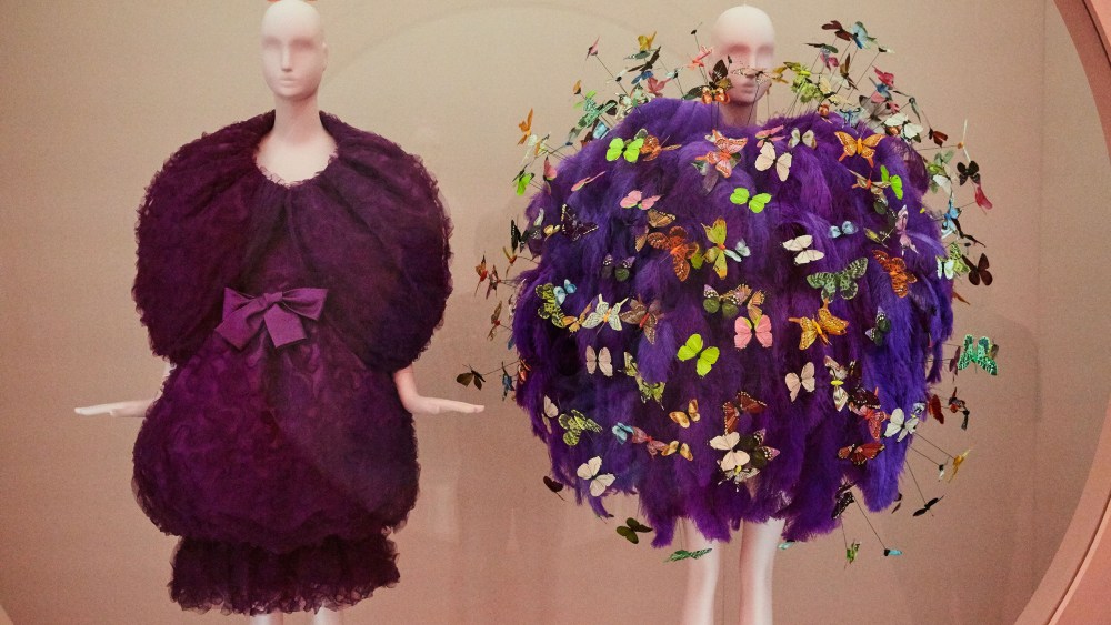 A Cristóbal Balenciaga evening ensemble from fall 1961 and a fall 2018 one from Jeremy Scott for Moschino embroidered with purple ostrich feathers, and polychrome printed feather and paper butterflies.