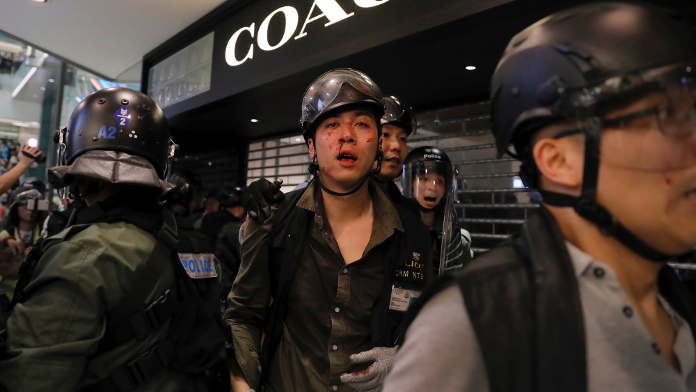 An injured policeman is escorted out by colleagues from New Town Plaza mall.