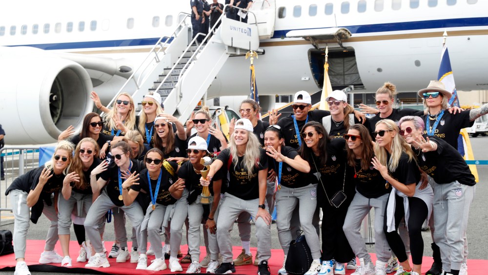 Julie Ertz, Megan Rapinoe, Alex Morgan. Members of the United States women's soccer team, winners of a fourth Women's World Cup, celebrate and pose with the trophy by their plane after arriving at Newark Liberty International Airport, in Newark, N.J. Julie Ertz holds the trophy, Megan Rapinoe, front right, gestures, and Alex Morgan, back left, also gesturesWWCup US Returns Home, Newark, USA - 08 Jul 2019