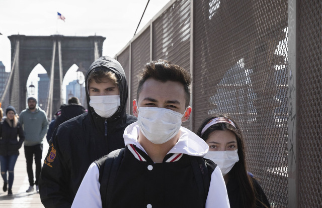People wear masks as they cross the Brooklyn Bridge, in New YorkVirus Outbreak , New York, United States - 16 Mar 2020