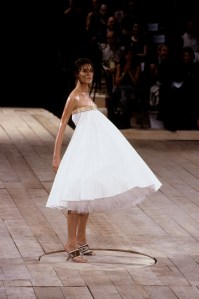 Shalom Harlow wearing strapless a-line white knee-length dress before being sprayed with paint in the Alexander McQueen RTW spring 1999 show.