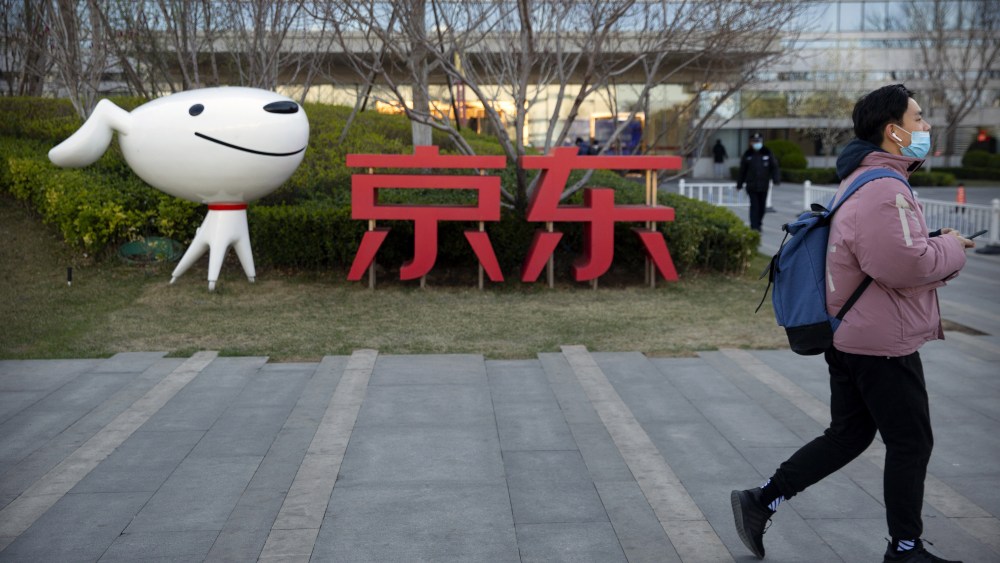 A man walks past the JD.com logo outside the company's headquarters in Beijing.