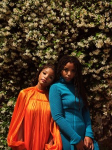 Chloe in Carolina Herrera's plaited rib tie turtleneck and flare skirt. Halle in Carolina Herrera's cape minidress.