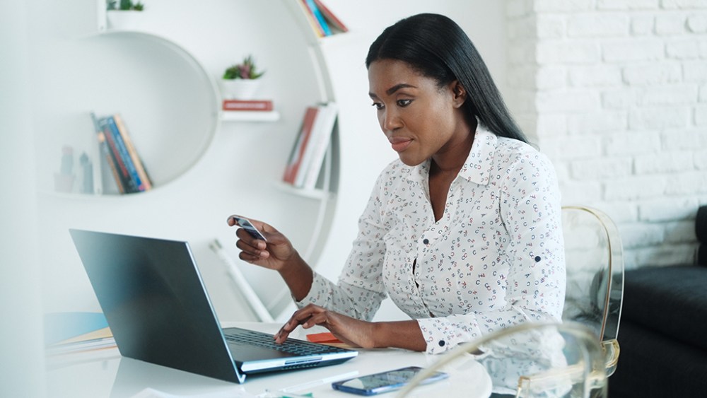 Black woman paying online purchase with credit card after shopping. African american people with laptop computer using card for internet transaction at home