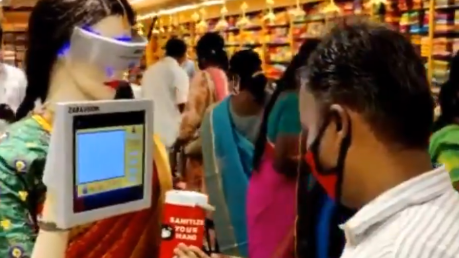 In a Pothys showroom in Madurai, India, a robot mannequin offers a shopper hand sanitizer while wearing one of the company's signature sarees.