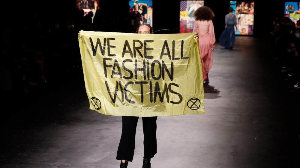 An activist displays a banner during Dior's Spring 2021 show.