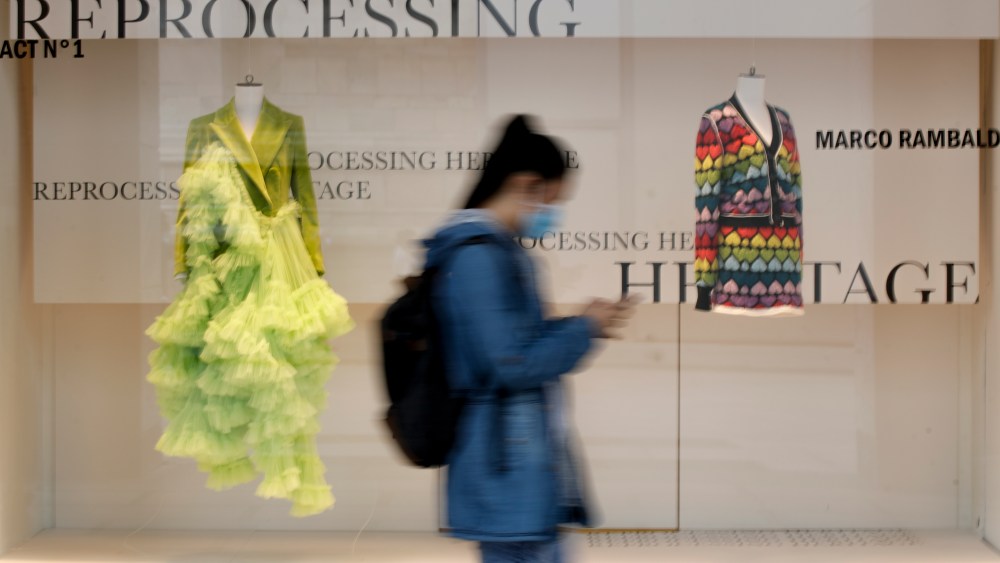 A woman wearing a mask walks past Milan's landmark department store, Rinascente, as young stylists present their collections, in Milan, Italy, Wednesday, Sept. 23, 2020. The Italian fashion industry is trying to inject optimism into the most dismal year on record for the luxury sector, staging 23 live runway shows and 37 presentations during a hybrid live-digital Milan Fashion Week that aims to excite consumers and connect with buyers. (AP Photo/Luca Bruno)