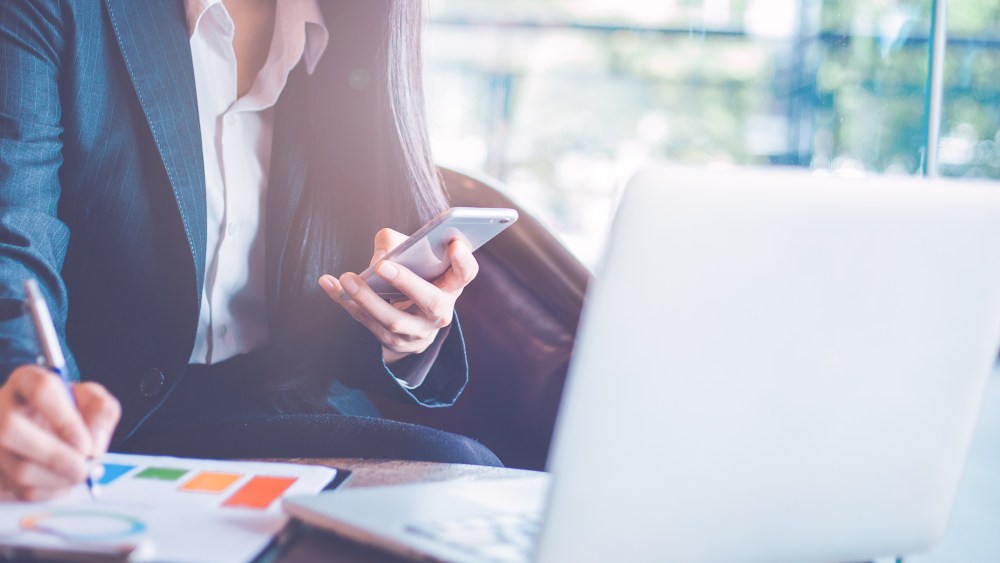 Business  woman uses a smartphone and writing on charts and graphs that show results.Web banner.