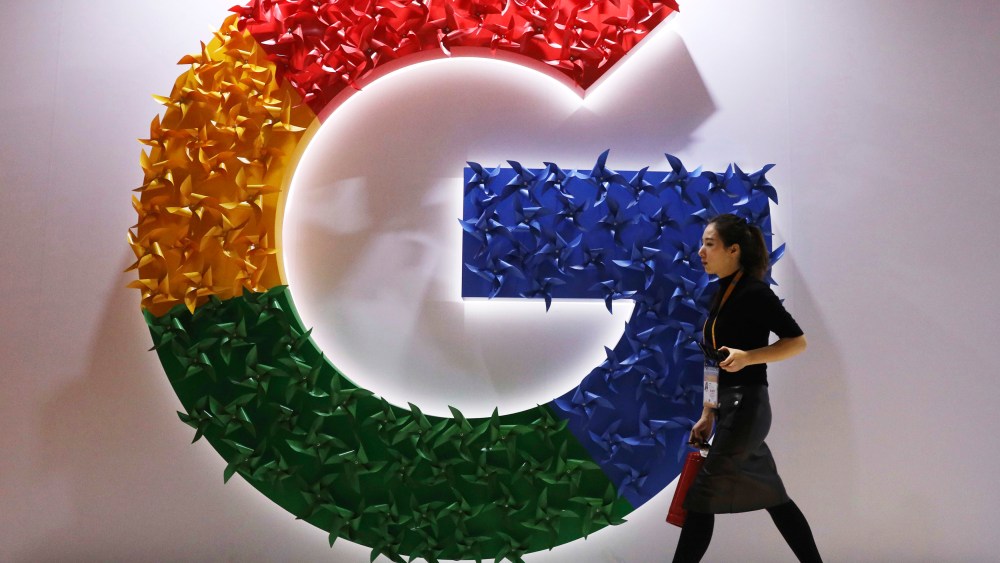 FILE - In this Monday, Nov. 5, 2018 file photo, a woman walks past the logo for Google at the China International Import Expo in Shanghai. Google says it's making progress on plans to revamp Chrome user tracking technology aimed at improving privacy even as it faces challenges from regulators and officials.  The company gave an update Monday, Jan. 25, 2021 on its work to remove from its Chrome browser so-called third-party cookies, which are used by a website's advertisers or partners and can be used to track user browsing habits across the internet.  (AP Photo/Ng Han Guan, File)