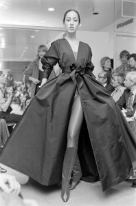 Model Pat Cleveland poses in a paper taffeta gala dress over a red satin body suit and boots from Halston's Fall 1977 Ready to Wear collection.
