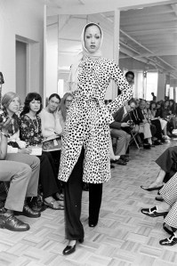 Model Pat Cleveland walks Halston's fall 1972 ready to wear fashion show in a dalmatian print wrap coat.