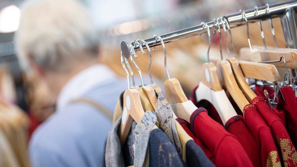 26 April 2019, Baden-Wuerttemberg, Stuttgart: Sustainably produced clothing hangs on hangers at the Fair Trade trade fair at a stand. There's a visitor behind the coat stand. Photo by: Sebastian Gollnow/picture-alliance/dpa/AP Images