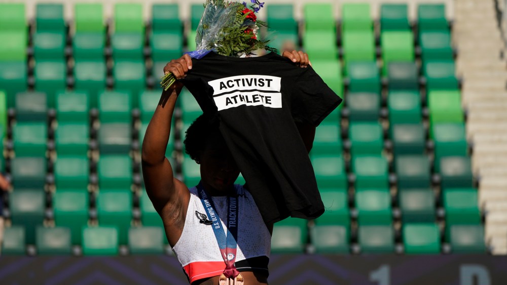 Gwendolyn Berry holds her T-shirt over her head during the metal ceremony after the finals of the women's hammer throw at the U.S. Olympic Track and Field Trials in Eugene, Ore. Tommie Smith, John Carlos and Berry are among the more than 150 educators, activists and athletes who signed a letter Thursday, July 22, urging the IOC not to punish participants who demonstrate at the Tokyo Games.