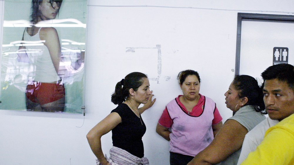 ** ADVANCE FOR WEEKEND MAY 8-9 ** Workers on the sewing floor take a break near a poster of a model wearing American Apparel garments, April 12, 2004, in Los Angeles. In an industry with a history of sweatshops, American Apparel is one of two Los Angeles firms convinced it can make money without underpaying or overworking employees. (AP Photo/Ric Francis)