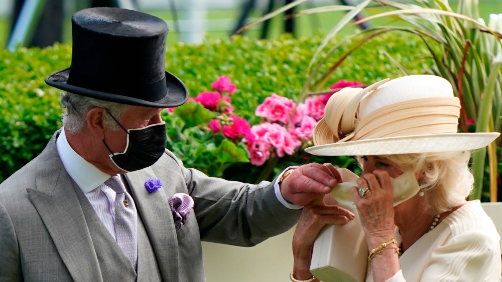 Royal Ascot 2021 - Day Two. The Prince of Wales helps the Duchess of Cornwall with her mask during day two of Royal Ascot at Ascot Racecourse. Picture date: Wednesday June 16, 2021. See PA story RACING Ascot. Photo credit should read: Andrew Matthews/PA Wire. RESTRICTIONS: Use subject to restrictions. Editorial use only, no commercial use without prior consent from rights holder. URN:60395516 (Press Association via AP Images)
