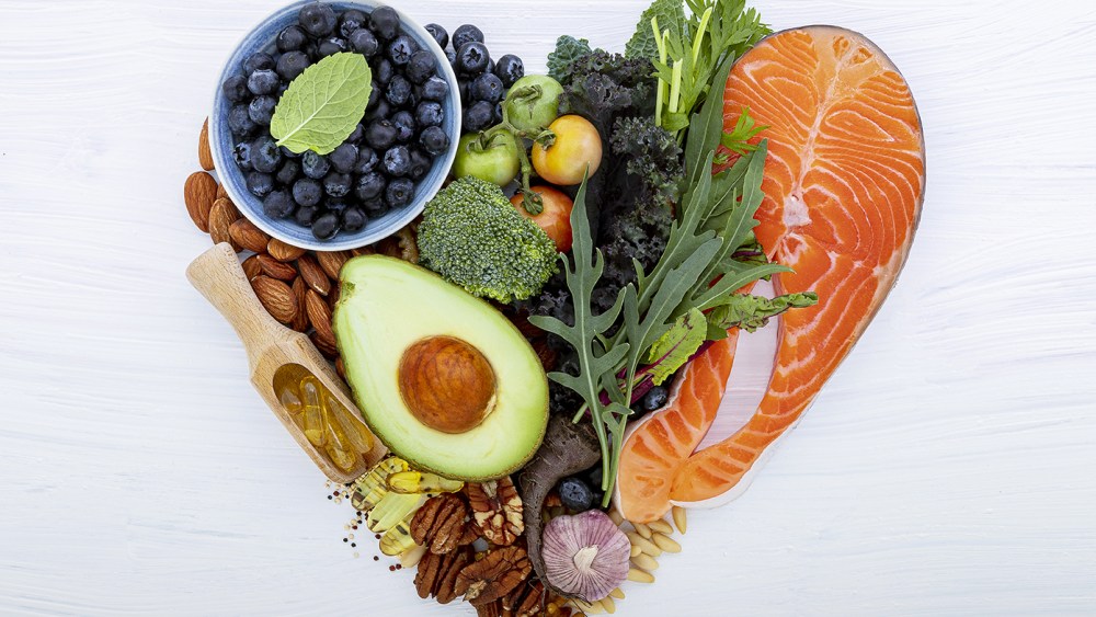 Heart shape of ketogenic low carbs diet concept. Ingredients for healthy foods selection on white wooden background. Balanced healthy ingredients of unsaturated fats for the heart and blood vessels.