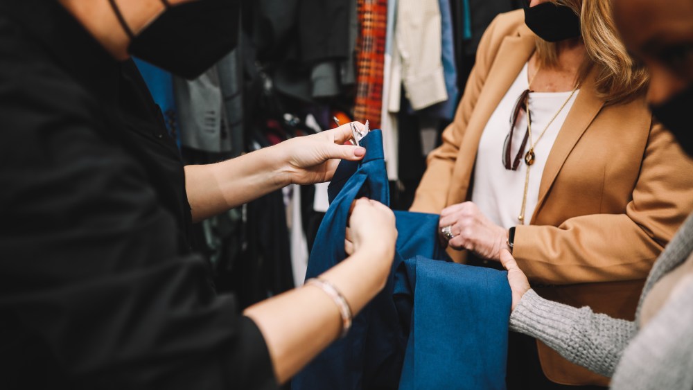 Small business owners inspect the stitching of blue denim up close, wearing masks and blazers.