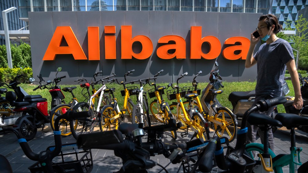 A man wearing a face mask walks past the offices of Chinese e-commerce firm Alibaba in Beijing.