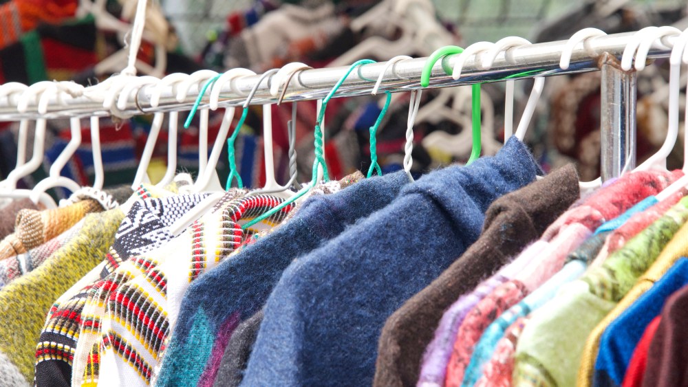 close up of clothing hanging on a rack at resale shop at street fair outside. Used clothing.
