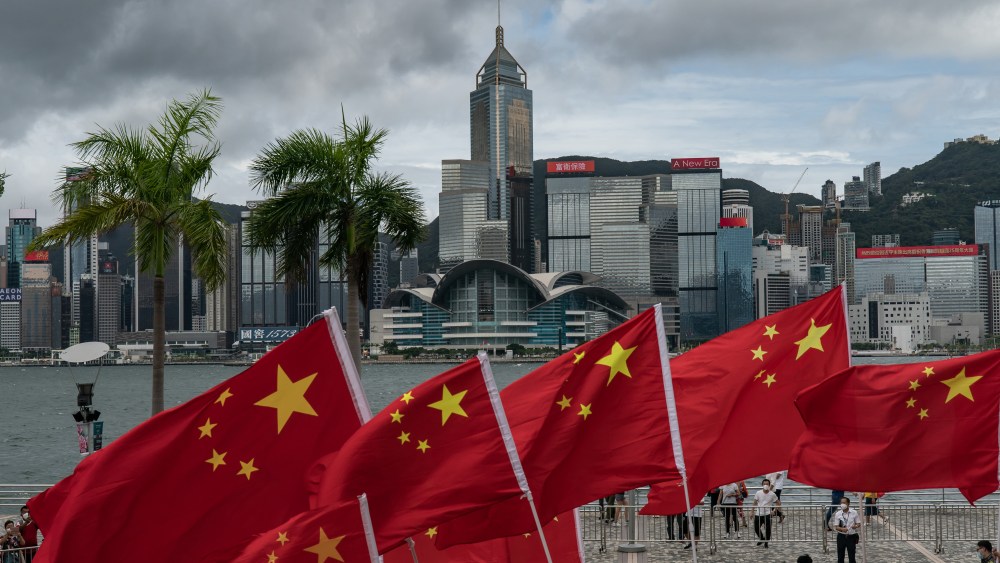 People wave Chinese national flags in front of the Victoria Harbour promenade on July 01, 2022 in Hong Kong, China.