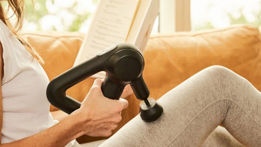 woman using theragun massage device