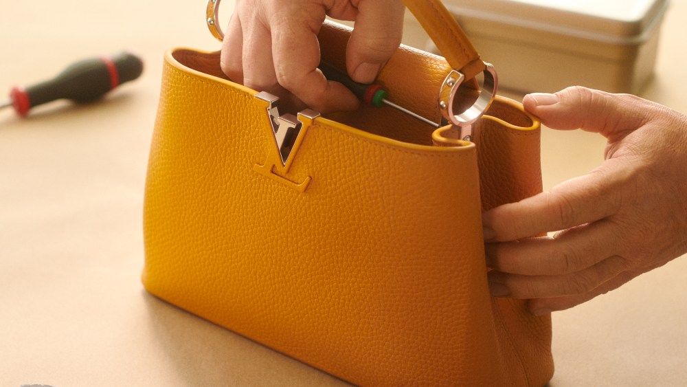 A mustard yellow Louis Vuitton bag sits amid a spread of workshop tools for repairing.
