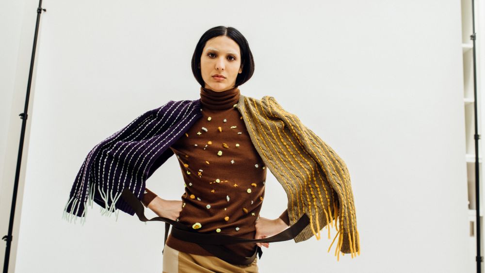An androgynous model sports The RealReal Recollection 04, posing with hands on hips and draped in scarves.