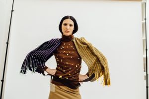 An androgynous model sports The RealReal Recollection 04, posing with hands on hips and draped in scarves.