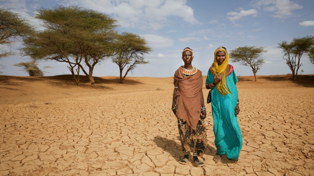 An image from Concern Worldwide features two African people dressed in colorful local clothing standing on desert plans with trees in the background.