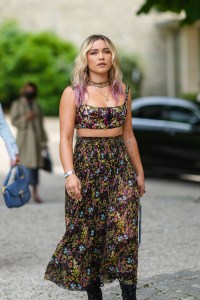 PARIS, FRANCE - JULY 05: Florence Pugh wears gold pendant earrings, a gold J'Adior chain necklace, a multicolored pearls necklace, gold necklace, a black tulle with multicolored flowers embroidered zipper tank-top / crop-top, a matching black tulle with multicolored flowers embroidered flowing midi skirt, a blue gray small Lady D-Lite hand bag from Dior, a silver watch, a gold ring, black shiny leather laces knees boots from Christian Dior, outside Dior, during Paris Fashion Week - Haute Couture Fall/Winter 2021/2022, on July 05, 2021 in Paris, France. (Photo by Edward Berthelot/Getty Images)