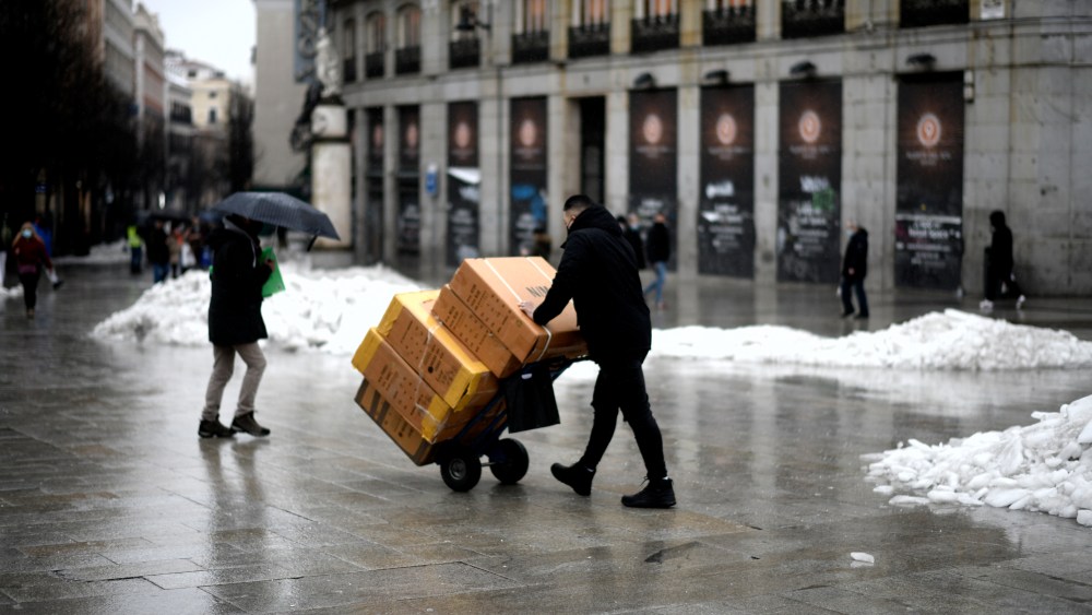 A delivery man carries some boxes through the Puerta del Sol on the same day as the arrival of the storm 'Gaetán', in Madrid, (Spain), on 20th January 2021. The snow storm and subsequent cold caused by the storm 'Filomena' ended yesterday to leave the storm 'Gaetán' that has started today causing abundant rain, wind and a more than remarkable thermal rise. In flat areas such as Madrid, still with the snow of 'Filomena' on the ground will not be exceeded with the fronts associated with 'Gaetan' 20 or 30 liters per square meter in 72 hours, from Wednesday to Friday, however, to this prediction, the Community of Madrid yesterday activated the level of pre-emergency of the Special Plan for Civil Protection to the risk of flooding given the situation of the presence of frozen snow on cornices, roofs of buildings and streets in the Community as a result of the Filomena storm. 20 JANUARY 2021;GAETAN;RAIN;STORM;MADRID Óscar Cañas / Europa Press 01/20/2021 (Europa Press via AP)