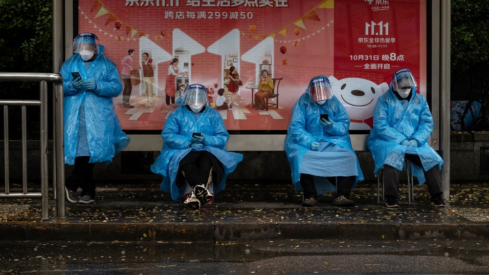 Epidemic control workers in front of a billboard advertising Chinas largest annual online shopping known as Singles' Day outside a locked down community in Beijing, China.