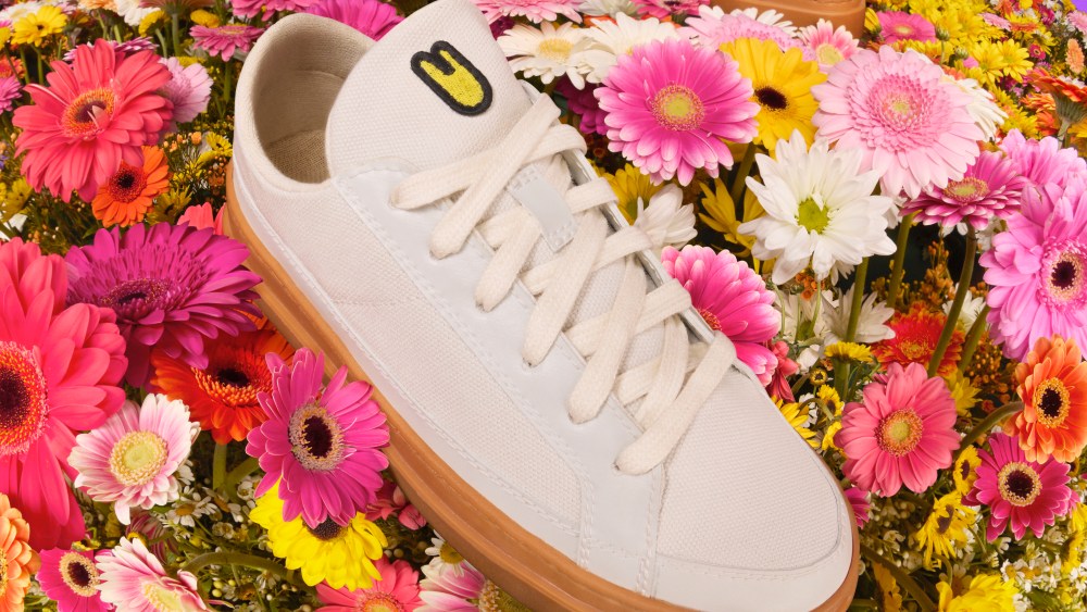 Unless Collective's plastic-free sneaker atop a bed of pink and yellow flowers.