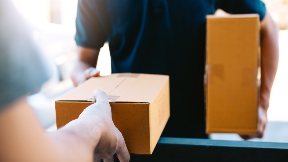 Close up of hands cargo staff are delivering cardboard boxes with parcels inside to the recipient's hand.