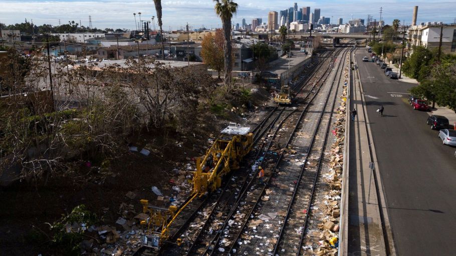 An aerial image from Jan. 16, 2022 shows the Los Angeles skyline as railroad workers repair a section of Union Pacific train tracks after a train derailed from the tracks, which are littered with thousands of opened boxes and packages stolen from cargo shipping containers targeted by thieves as the trains stop in downtown Los Angeles, California.